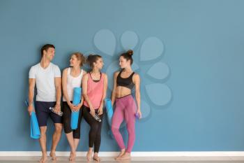 Group of people with yoga mats near color wall�