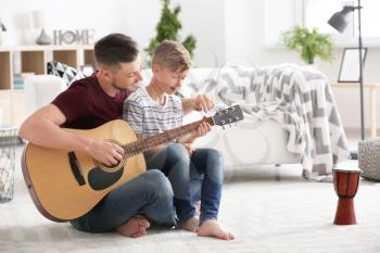Father teaching his son to play guitar at home�