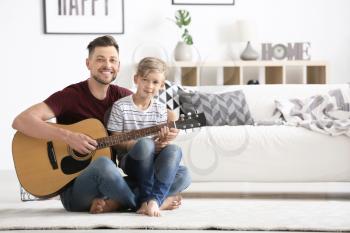Father teaching his son to play guitar at home�