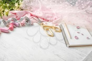 Composition with color threads and sewing accessories on white wooden background�