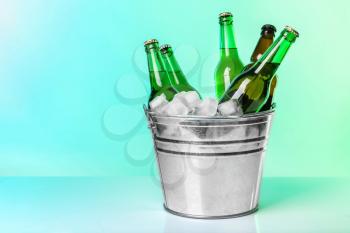 Bottles of beer in ice bucket on color background�