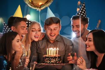 Young man with friends and birthday cake in club�