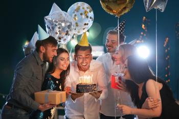 Young man with friends and birthday cake in club�