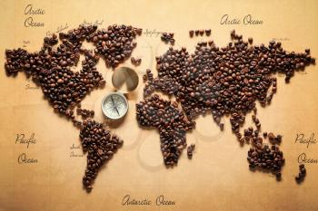 World map made of roasted coffee beans with compass, top view�