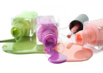 Open bottles with spilled nail polishes and brushes on white background�