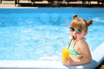 Cute little girl drinking juice in swimming pool�