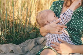 Woman breastfeeding her little son outdoors�