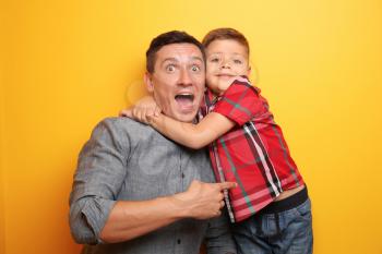 Emotional portrait of little boy and his dad on color background�