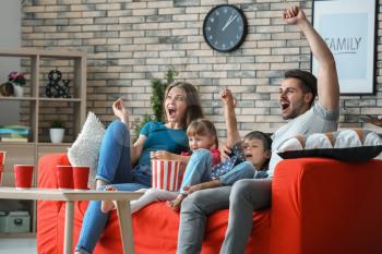 Family watching TV on sofa at home�