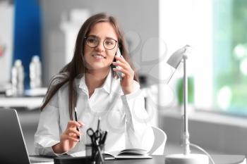 Young businesswoman talking by mobile phone in office�