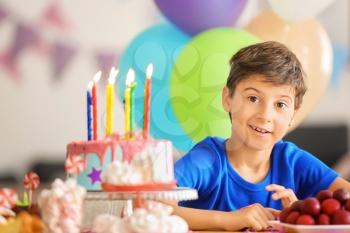 Cute little boy at table with birthday cake�