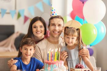 Happy family celebrating birthday at table with cake�