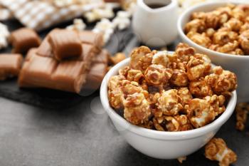 Bowl with delicious caramel popcorn on grey table, closeup�
