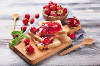 Composition with slices of bread and delicious strawberry jam on wooden table�