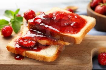 Slices of bread with delicious strawberry jam on board, closeup�