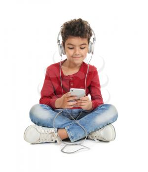 Cute little boy with headphones listening to music on white background�