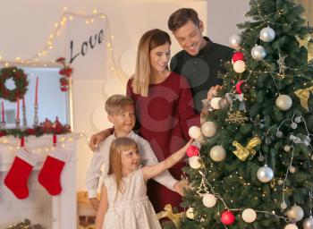 Family decorating beautiful Christmas tree in room�
