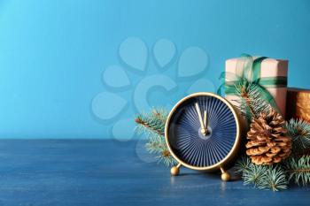 Alarm clock with gifts and fir branches on color background. Christmas countdown�