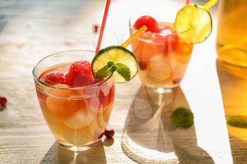 Glass of delicious cocktail with melon balls on light table�