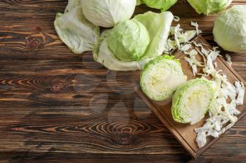 Wooden board with cut cabbage on table�
