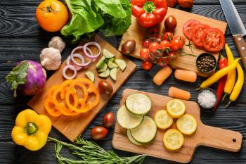 Cutting boards and many fresh vegetables on wooden background�