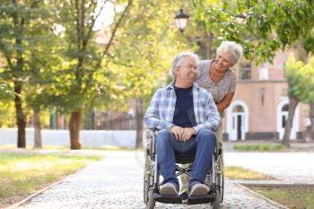 Happy senior man in wheelchair and his wife outdoors�