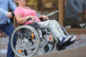 Senior woman in wheelchair and her husband on ramp outdoors�