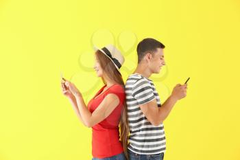Young couple with mobile phones on color background�