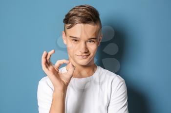 Teenage boy showing OK gesture on color background�