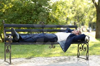 Handsome young businessman resting on bench in park�