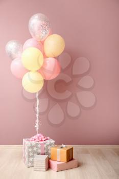 Colorful air balloons and gift boxes near pink wall�