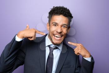 Portrait of happy African-American businessman on color background�