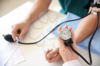 Female doctor measuring blood pressure of male patient in hospital�