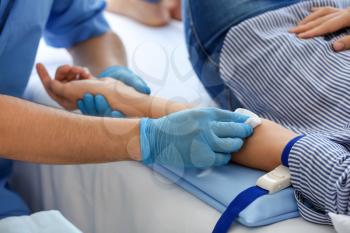 Male nurse preparing female donor for blood transfusion in hospital�