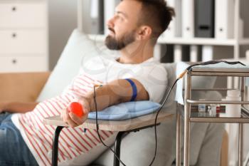 Man with grip ball donating blood in hospital�
