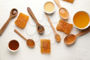 Composition with honey, spoons and honeycombs on white table�