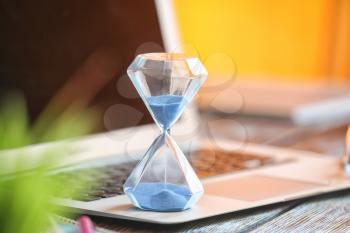 Hourglass on laptop keyboard. Time management concept�
