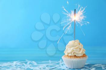 Delicious cupcake with sparkler on color background�