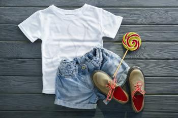 Stylish outfit with shoes and lollipop on wooden background�