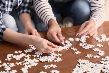 Young couple doing jigsaw puzzle at home, closeup�