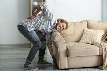 Young man suffering from back pain after carrying heavy furniture�