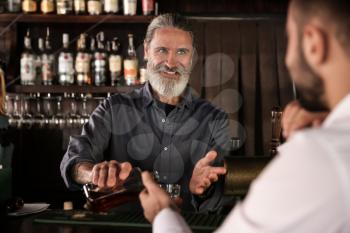 Senior barman serving client in pub�