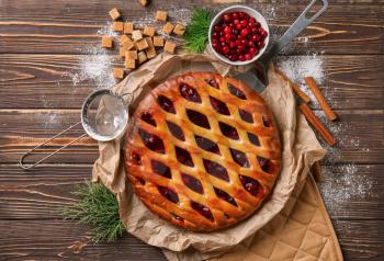Tasty Christmas pie stuffed with cranberries on wooden table�