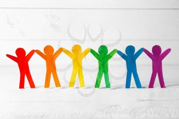 Rainbow paper human figures on white table. LGBT concept�