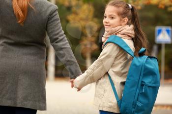 Cute girl going to school with her mother outdoors�
