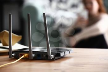 Modern wi-fi router on wooden table in room�