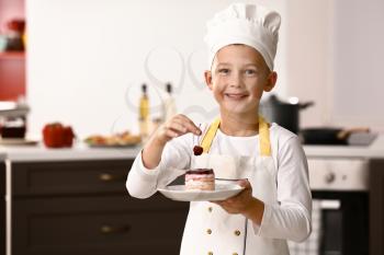 Cute little chef with tasty dessert in kitchen�