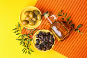 Bottle of oil with olives on color background�