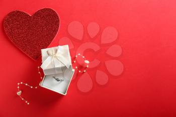 Beautiful box with engagement ring on color background�