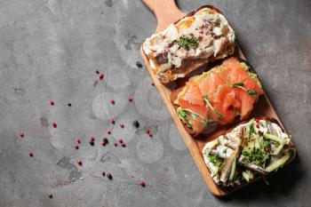 Different open sandwiches with fish on grey table�